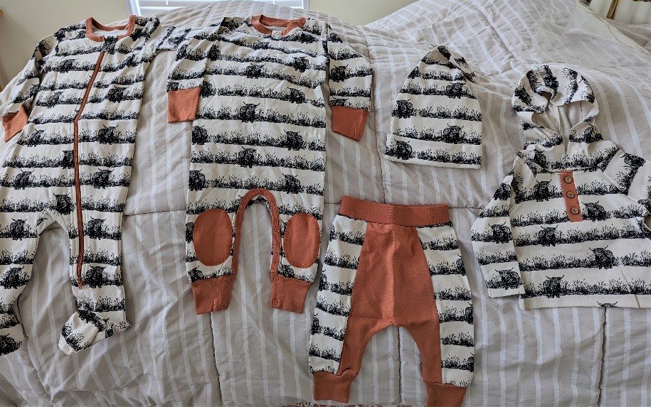 Variety of baby clothes items that feature Highland cattle graphics on them